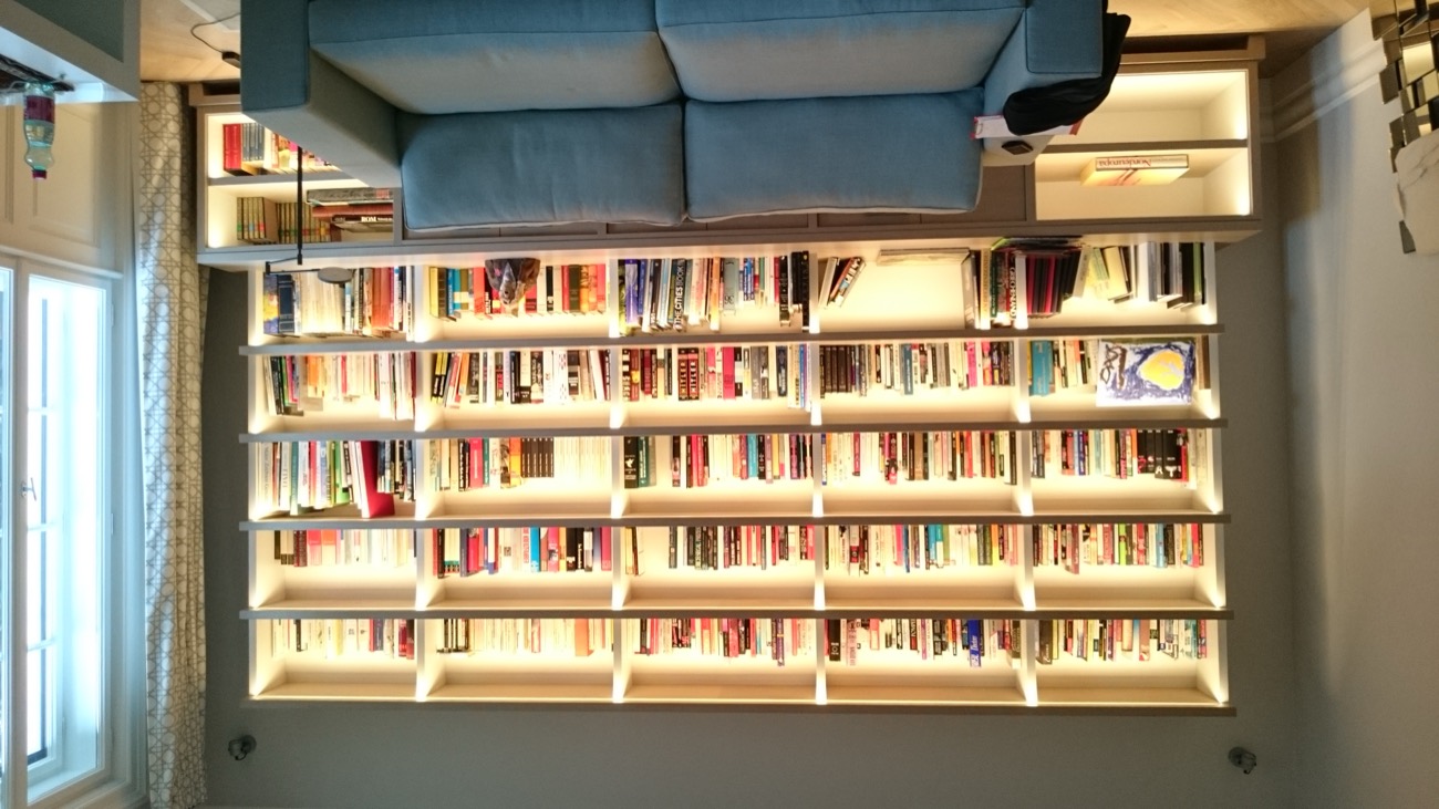 Beleuchtete Bücherwand am Fenster